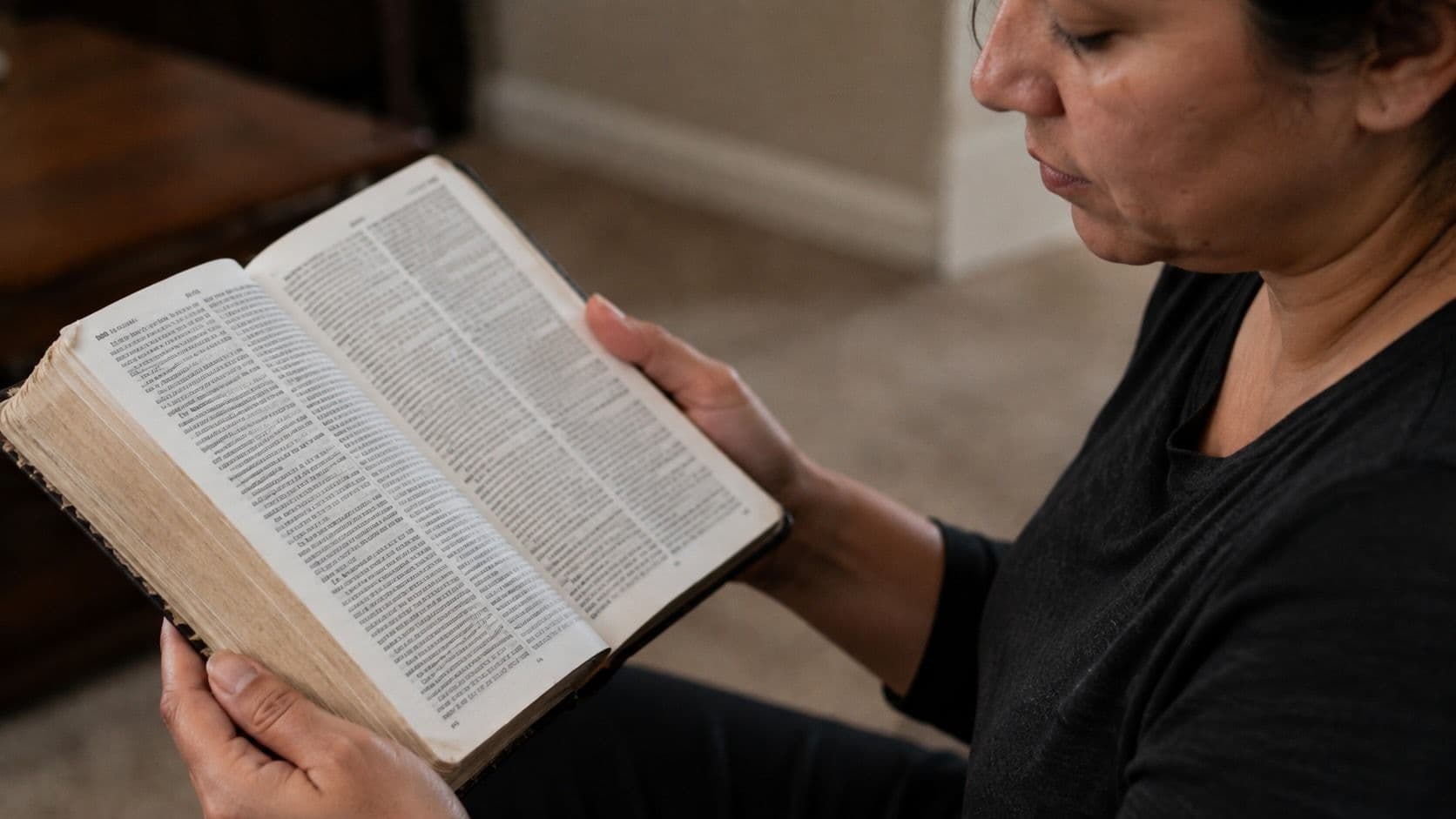 A person holding an open leather bound Holy Bible